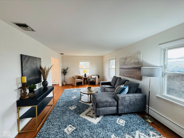 living room featuring a wealth of natural light, a baseboard radiator, wood finished floors, and visible vents