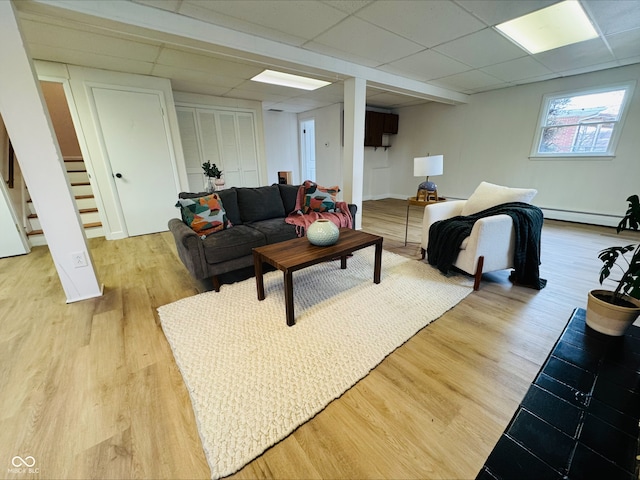 living room with light wood-type flooring, stairway, and a drop ceiling