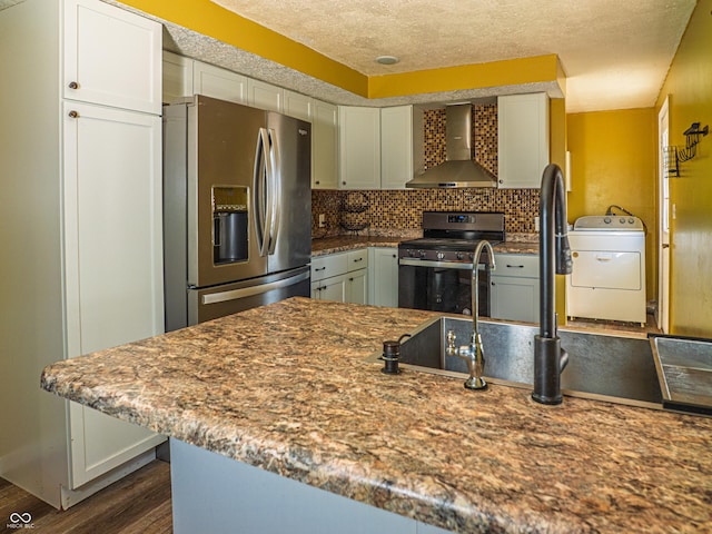 kitchen with dark wood-style flooring, wall chimney range hood, appliances with stainless steel finishes, backsplash, and washer / clothes dryer