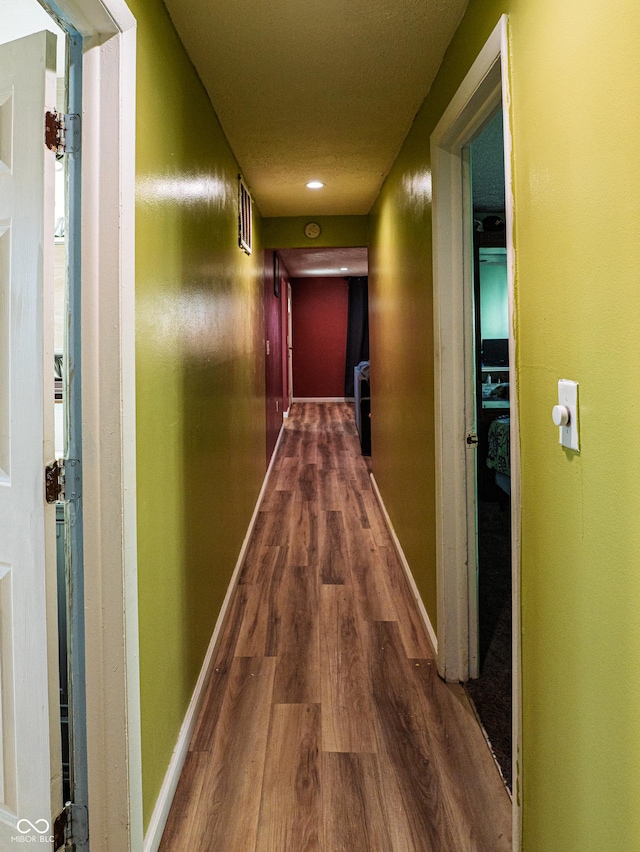 corridor with baseboards and wood finished floors