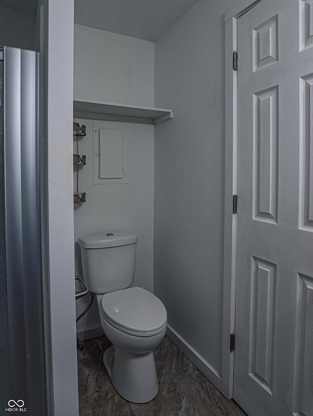 bathroom featuring toilet, baseboards, and a textured ceiling