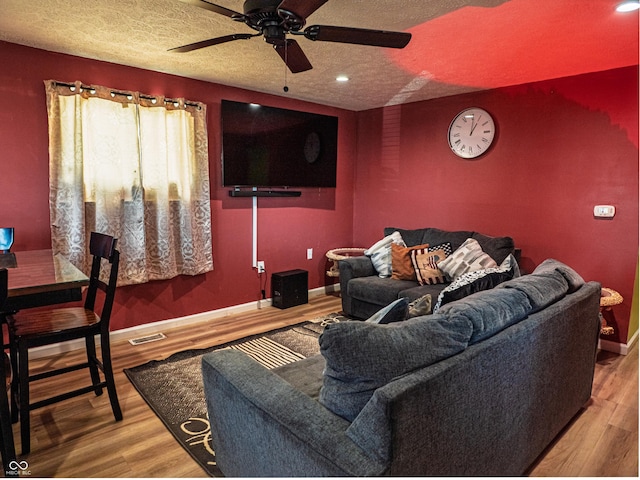 living room featuring baseboards, a textured ceiling, visible vents, and wood finished floors