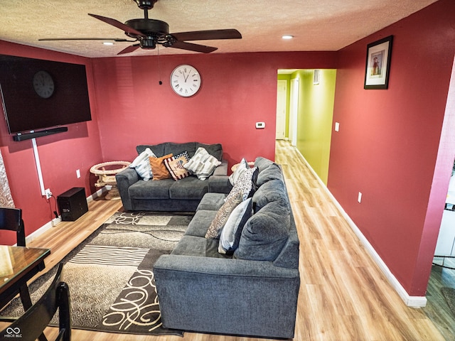 living area with ceiling fan, a textured ceiling, baseboards, and wood finished floors