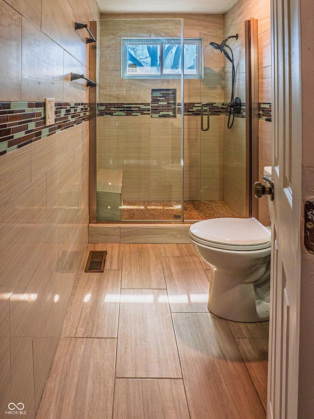 bathroom with toilet, a shower stall, and visible vents