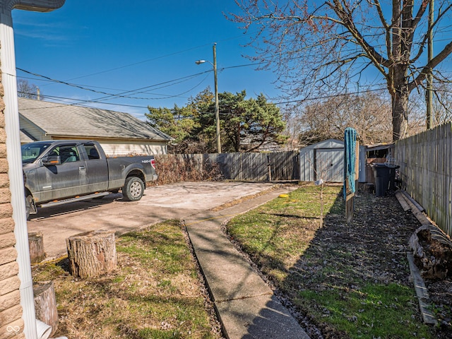 view of yard featuring a fenced backyard, an outdoor structure, a storage shed, and a patio