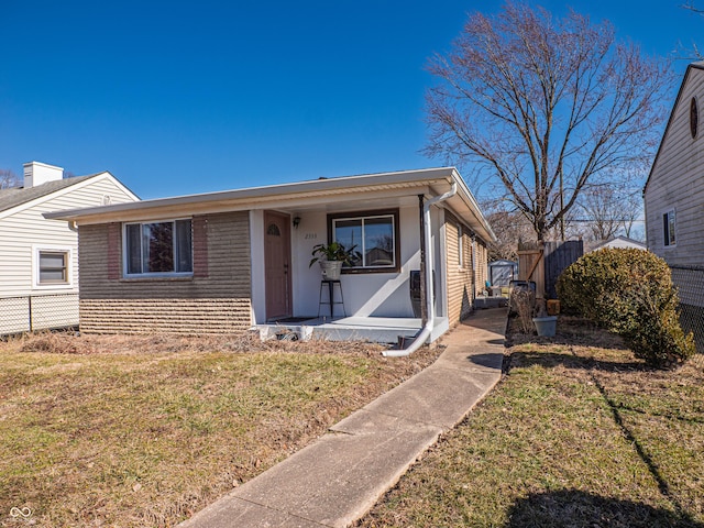 view of front of property with a porch, brick siding, fence, and a front lawn