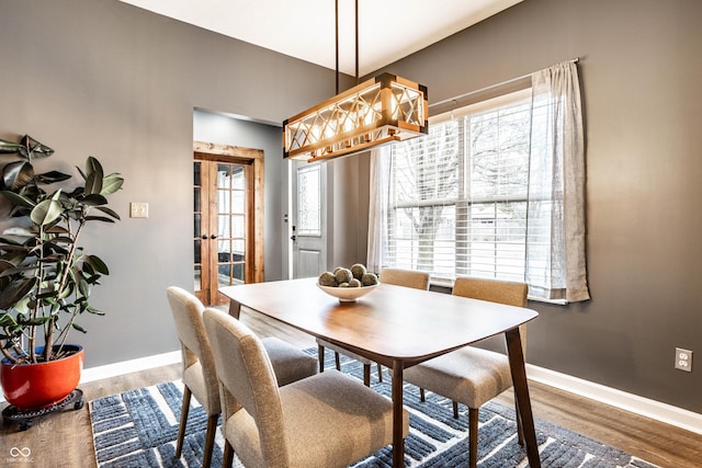 dining space with wood finished floors, baseboards, and french doors