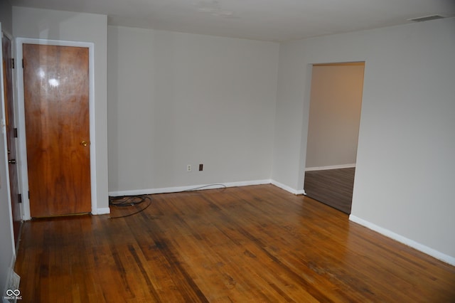 unfurnished room featuring dark wood-type flooring, visible vents, and baseboards