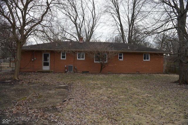 back of property featuring a chimney, crawl space, brick siding, and central AC