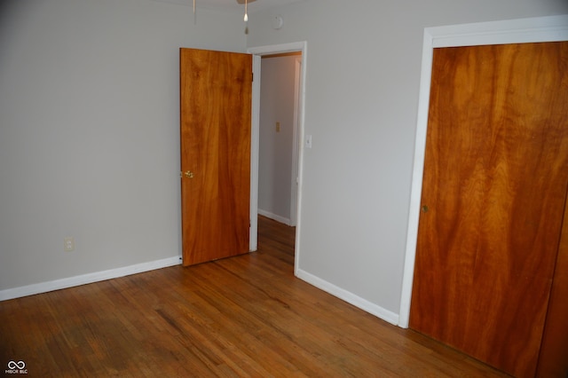 unfurnished bedroom featuring a closet, wood finished floors, and baseboards