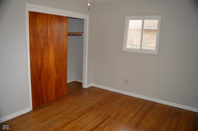 unfurnished bedroom with a closet, baseboards, and wood finished floors