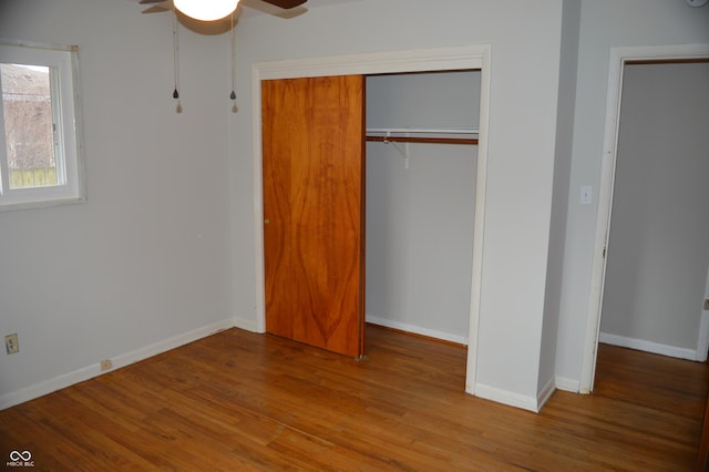 unfurnished bedroom featuring ceiling fan, a closet, light wood-type flooring, and baseboards