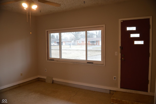 foyer entrance with a textured ceiling, carpet, a ceiling fan, and baseboards