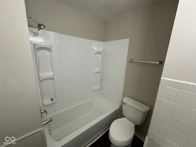 bathroom with toilet, tub / shower combination, and tile walls