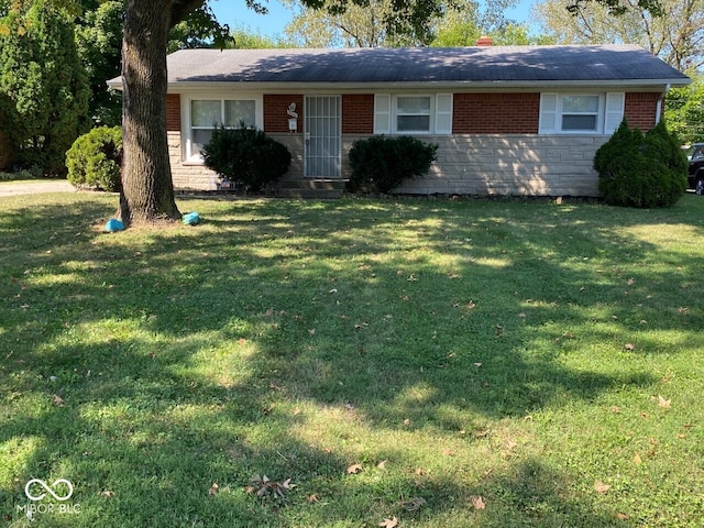 ranch-style home with brick siding, a chimney, stone siding, and a front yard