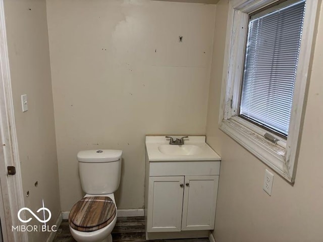 half bathroom with toilet, baseboards, and vanity