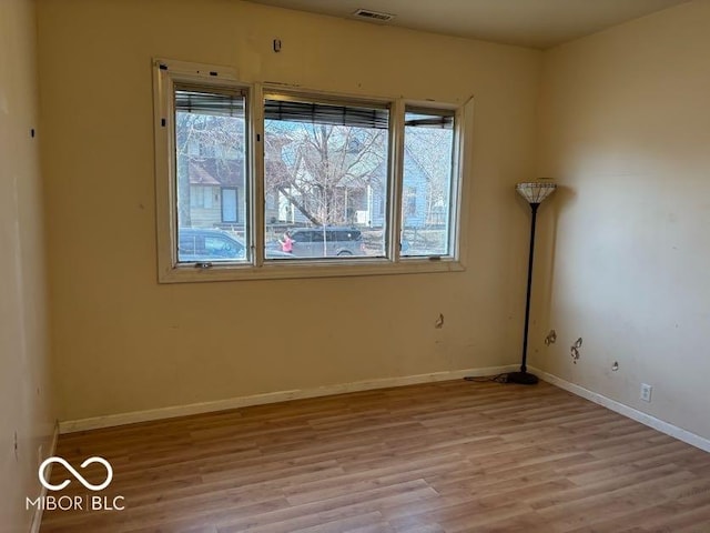 spare room featuring wood finished floors, visible vents, and baseboards