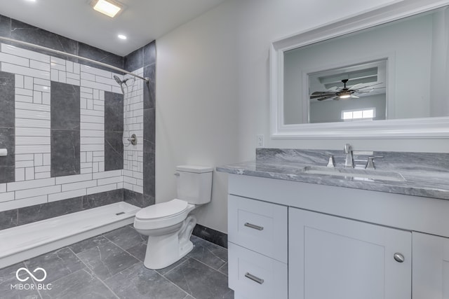 bathroom with toilet, baseboards, tiled shower, and vanity