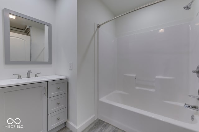 full bath with wood finished floors, vanity, bathing tub / shower combination, and baseboards