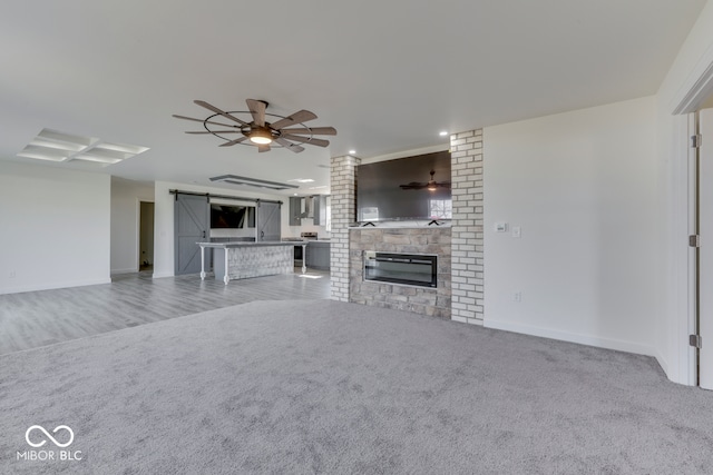 unfurnished living room with ceiling fan, a fireplace, baseboards, and light colored carpet