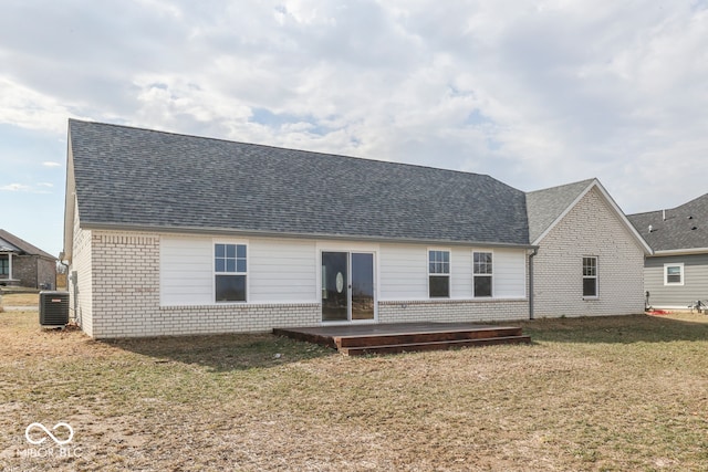 back of property with roof with shingles, a lawn, and brick siding