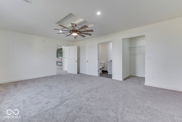 unfurnished bedroom with a walk in closet, carpet flooring, connected bathroom, and baseboards