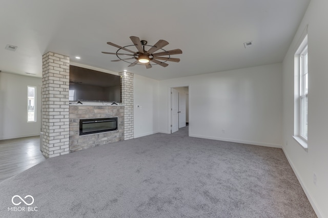 unfurnished living room featuring ceiling fan, a fireplace, visible vents, and baseboards