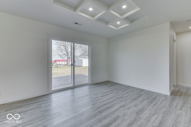 empty room with coffered ceiling, visible vents, and baseboards