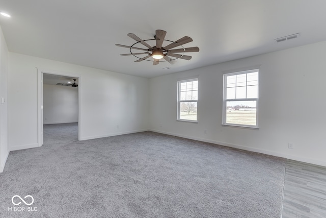 unfurnished room with a ceiling fan, visible vents, and baseboards