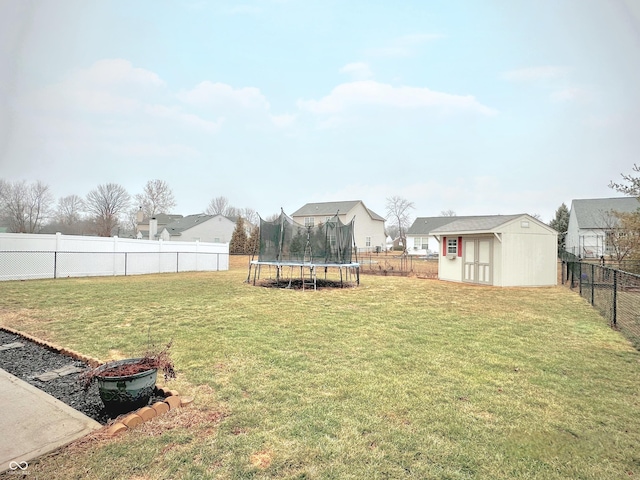 view of yard featuring a fenced backyard, a shed, an outdoor structure, and a trampoline