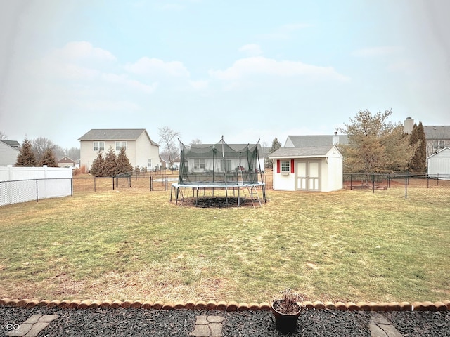 view of yard with a storage unit, a fenced backyard, an outdoor structure, and a trampoline