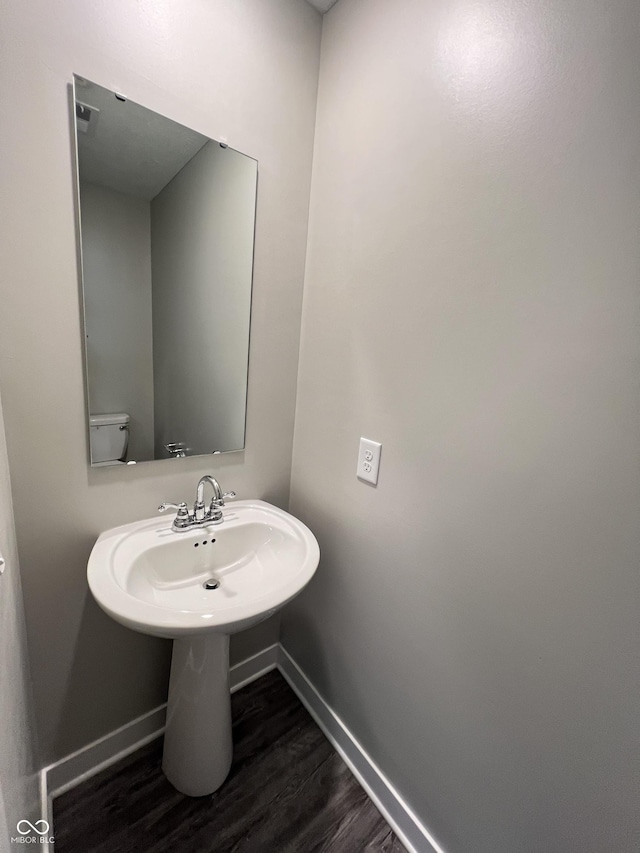 half bathroom featuring toilet, baseboards, and wood finished floors