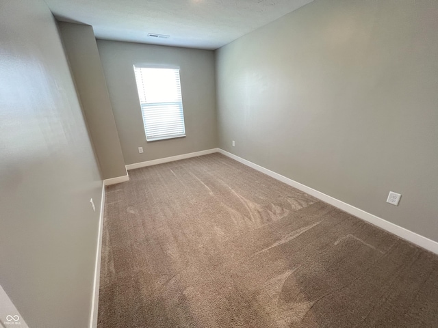 unfurnished room with carpet flooring, visible vents, and baseboards