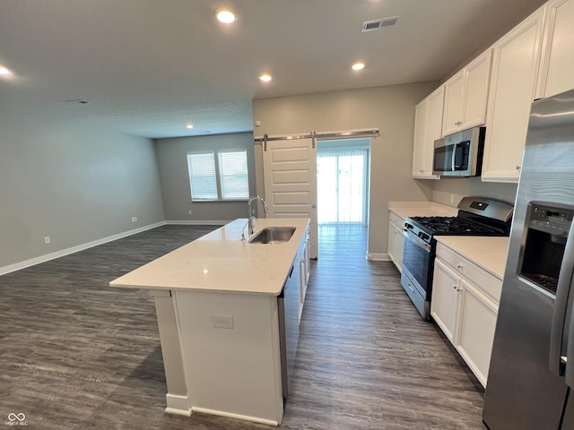 kitchen featuring a barn door, a sink, white cabinetry, appliances with stainless steel finishes, and an island with sink