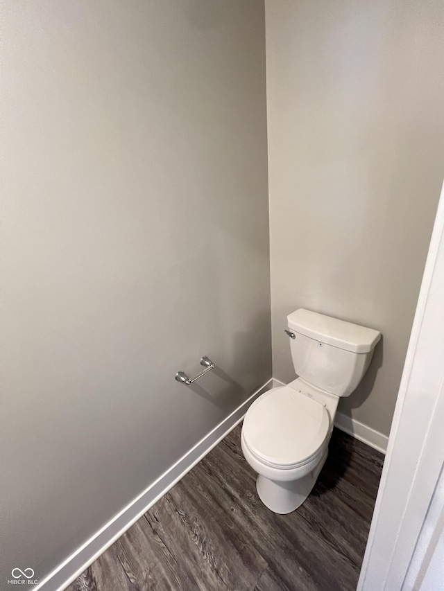 bathroom with baseboards, toilet, and wood finished floors