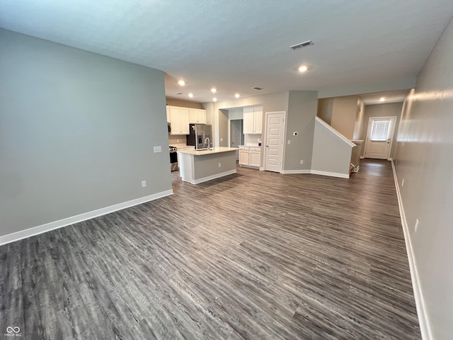 unfurnished living room featuring dark wood-style floors, visible vents, and baseboards