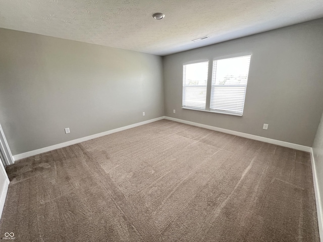 carpeted spare room featuring visible vents, baseboards, and a textured ceiling