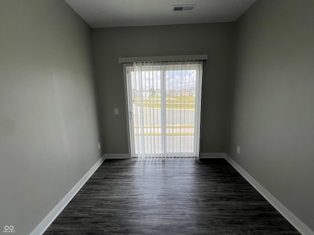 unfurnished room featuring baseboards, visible vents, and dark wood finished floors