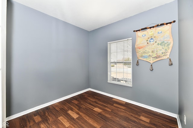 spare room featuring dark wood finished floors and baseboards