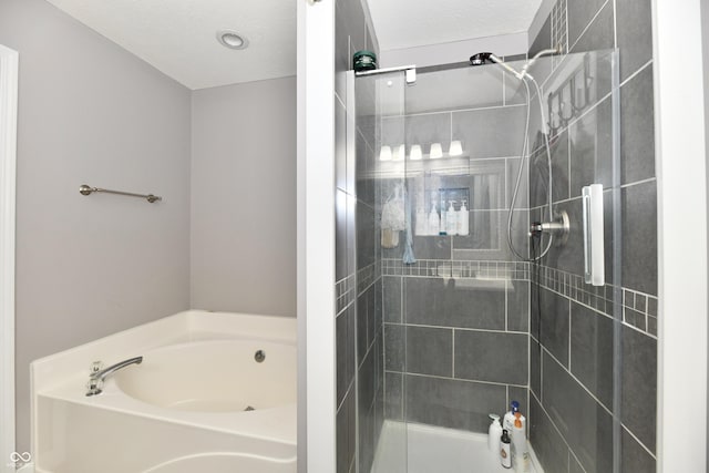 full bath featuring a textured ceiling, a stall shower, and a bath