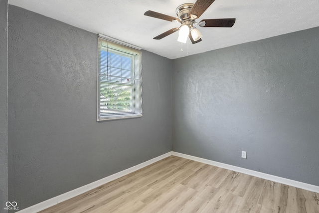 spare room featuring ceiling fan, a textured wall, light wood-style flooring, and baseboards