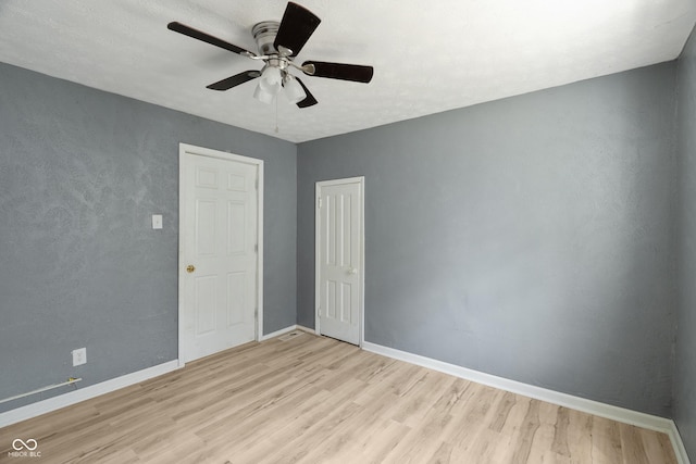 spare room with light wood-type flooring, ceiling fan, and baseboards