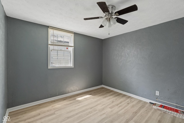 empty room with baseboards, a textured wall, ceiling fan, a textured ceiling, and light wood-style floors