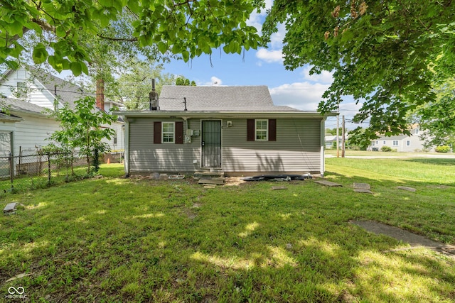 view of front facade featuring entry steps, fence, and a front lawn