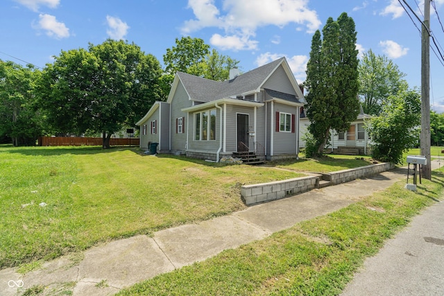 bungalow-style house with entry steps, a shingled roof, a chimney, fence, and a front yard