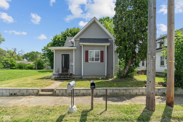 view of front facade with a front yard and roof with shingles