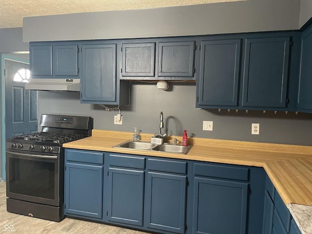 kitchen featuring stainless steel range with gas cooktop, a sink, light countertops, under cabinet range hood, and blue cabinets