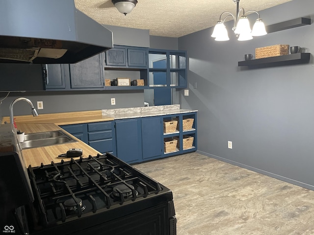 kitchen with under cabinet range hood, open shelves, blue cabinetry, a textured ceiling, and a sink