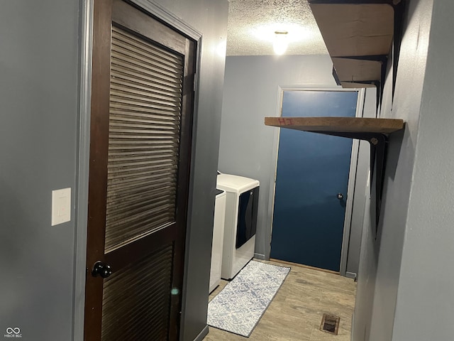 washroom with visible vents, a textured ceiling, separate washer and dryer, light wood finished floors, and laundry area