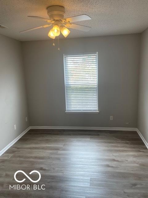 8249 Retreat Ln, Indianapolis, IN 46259 - spare room with a textured ceiling, baseboards, ceiling fan, and wood finished floors